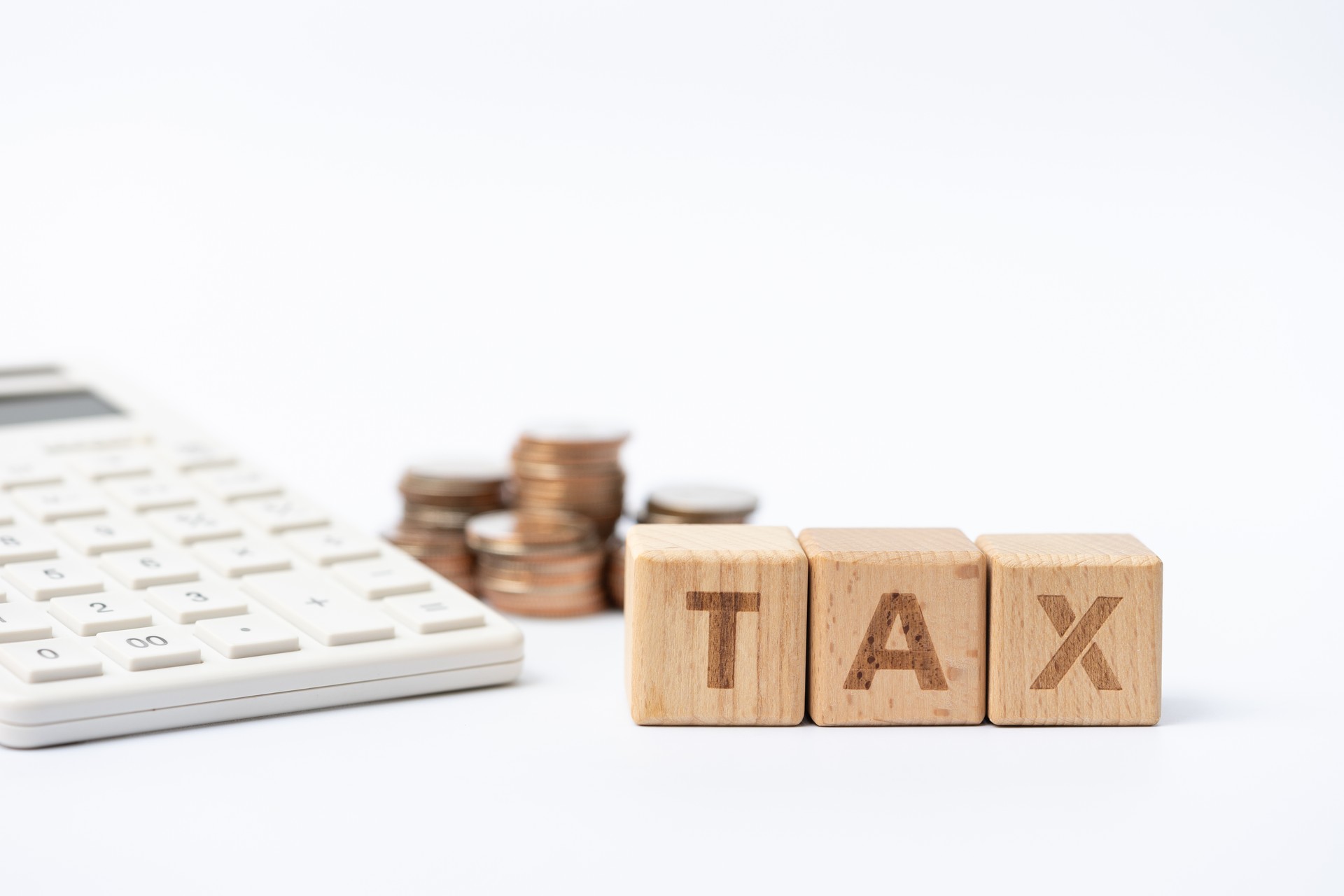 Word block "TAX", calculator, and pile of coins. Income, expenses, tax, financial data.